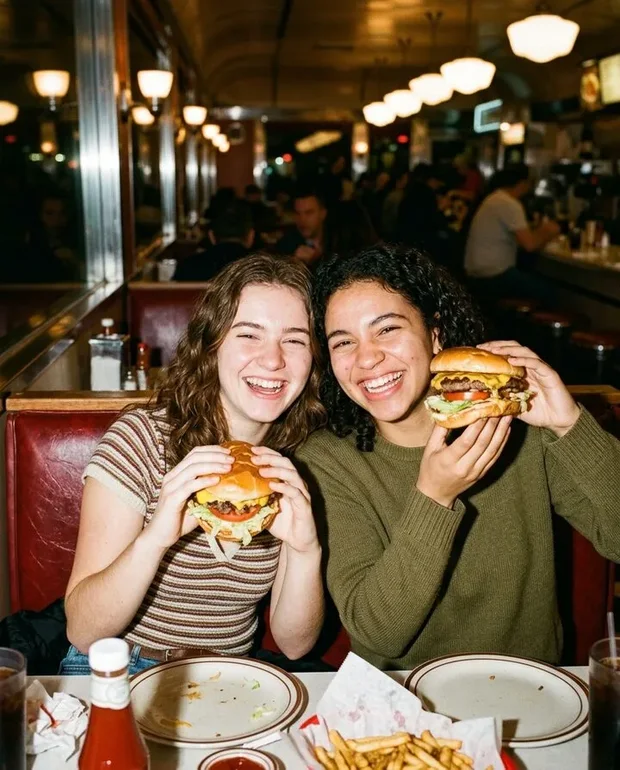Twee vrienden houden lachend hun cheeseburgers omhoog
