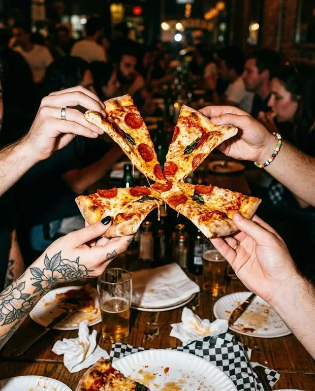 Handen die pizzapunten tegen elkaar tikken als een toost